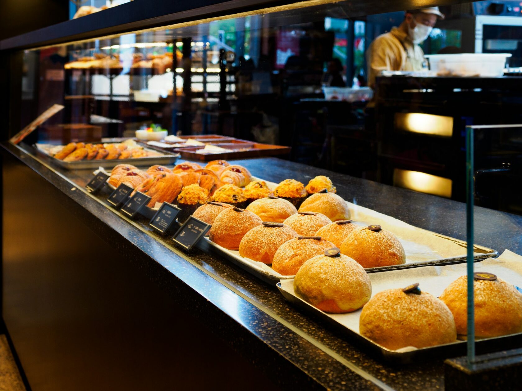 Interior da padaria com balcão de madeira e pão acabado de cozer